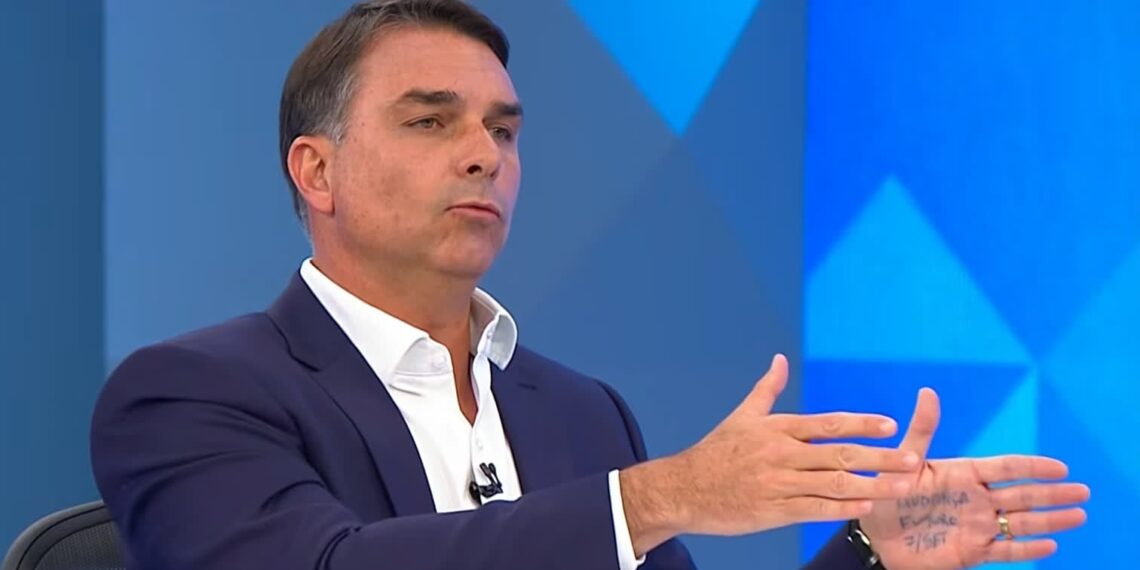 Flávio anota mensagens na mão durante sabatina na Globo