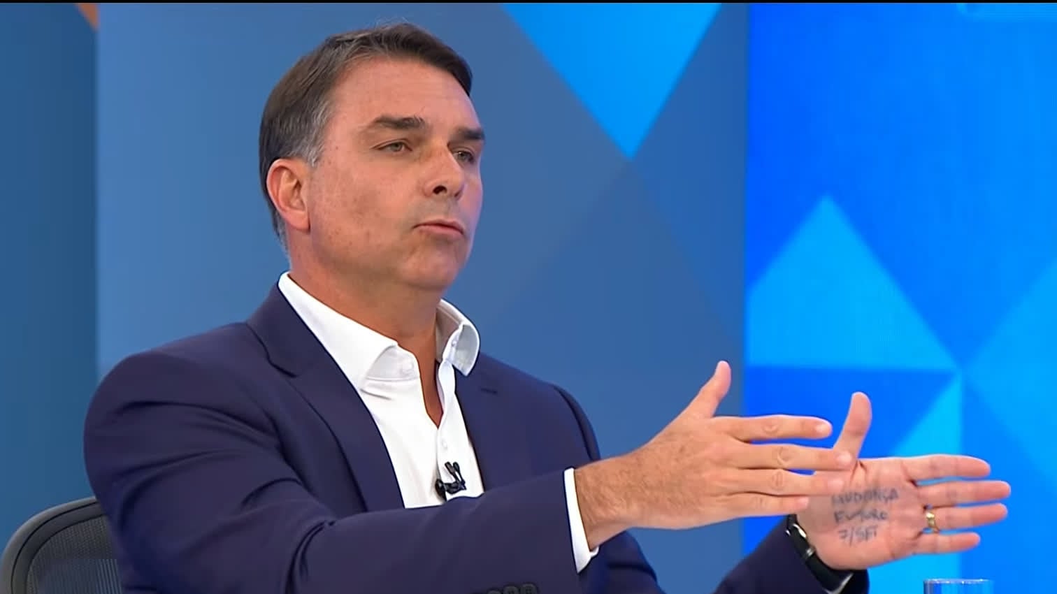 Flávio anota mensagens na mão durante sabatina na Globo